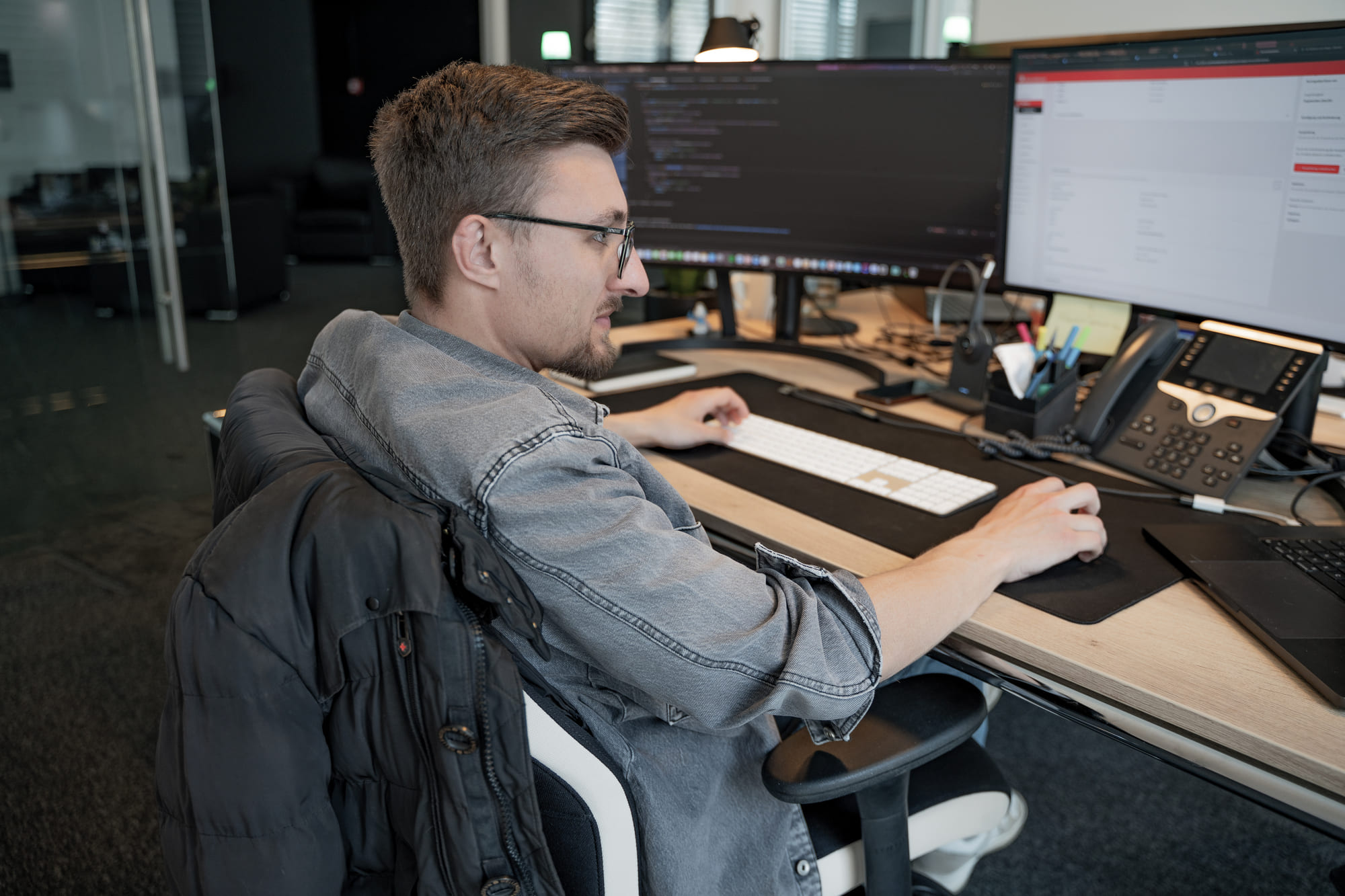 Pascal von digitalbynature® am Arbeitsplatz mit Code auf zwei Monitoren im Büro in Heppendorf