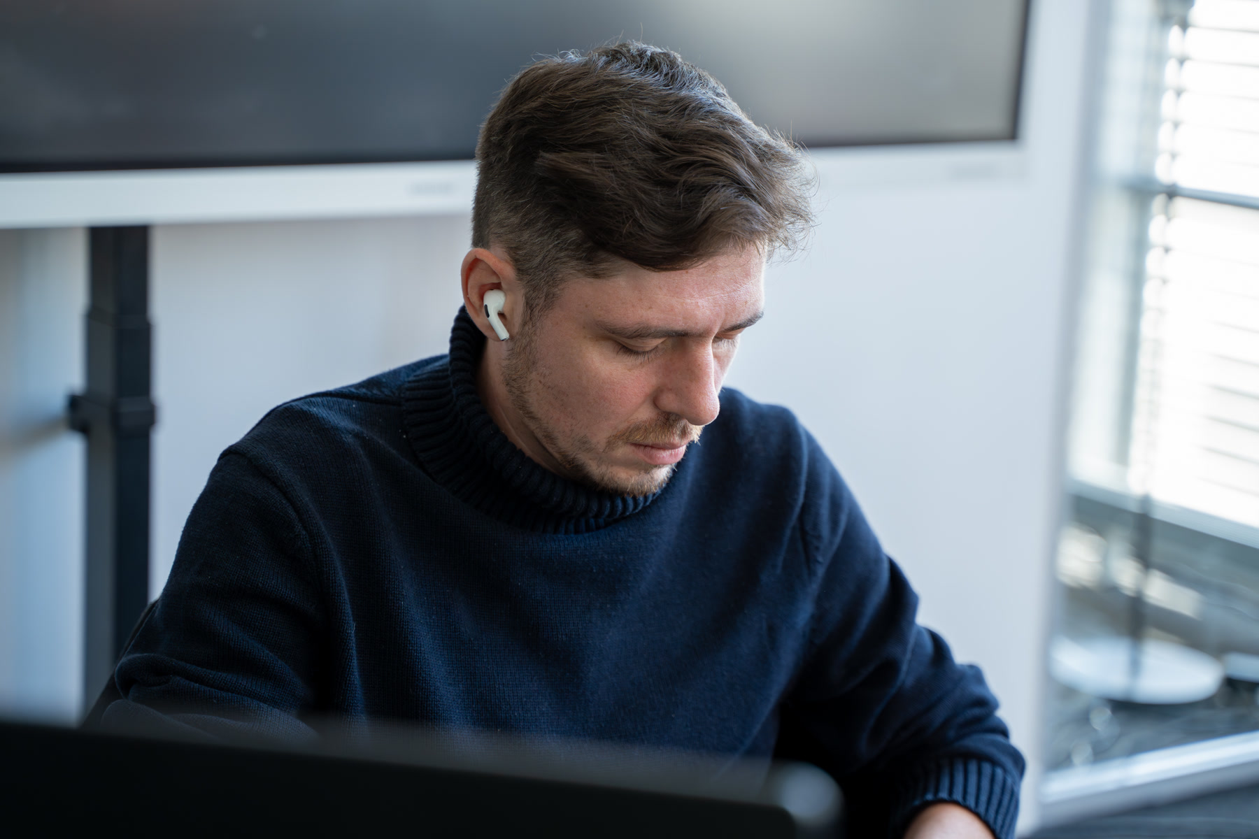 Entwickler von digitalbynature® mit Earbuds am Arbeitsplatz